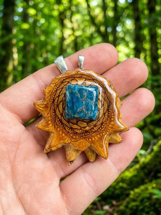 Hand holding sun-shaped pinecone pendant with blue stone, nature-inspired resin jewelry