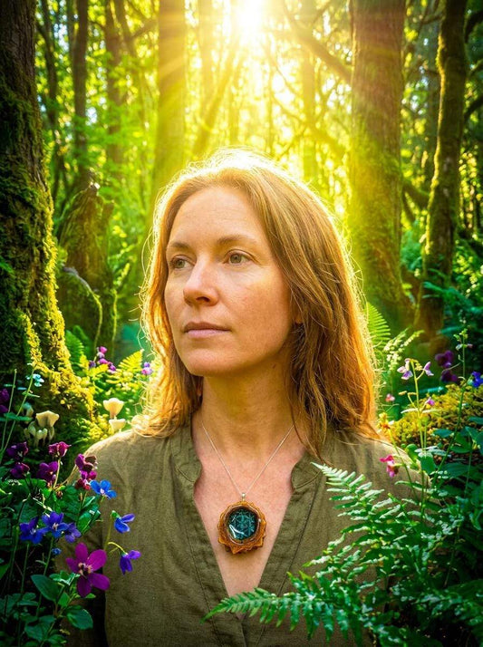 Woman wearing handmade pinecone pendant necklace in sunlit forest with wildflowers