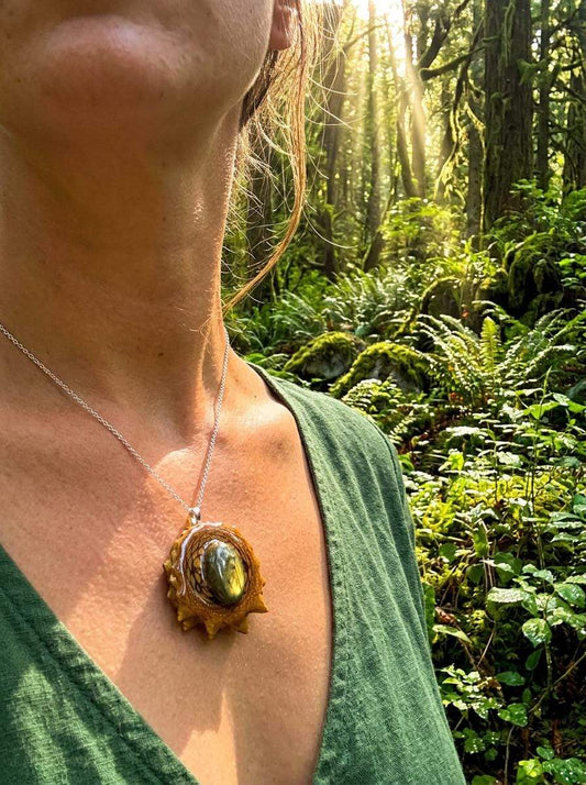 Pinecone pendant necklace with resin and gemstone, worn in forest setting