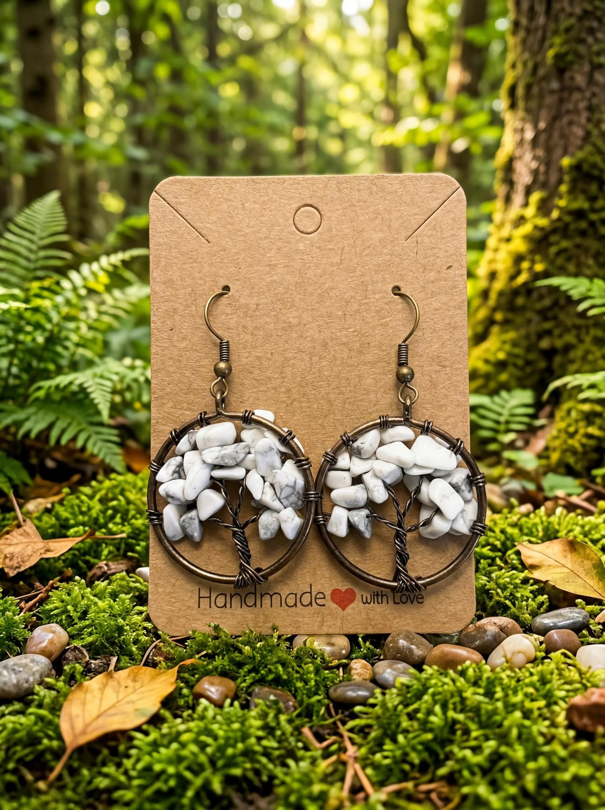 Handmade wire-wrapped earrings with white stone chips, displayed on a forest moss background.
