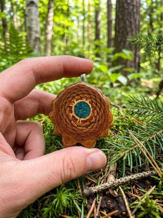 Hand holding custom pinecone pendant with resin inlay, forest backdrop, nature-inspired jewelry
